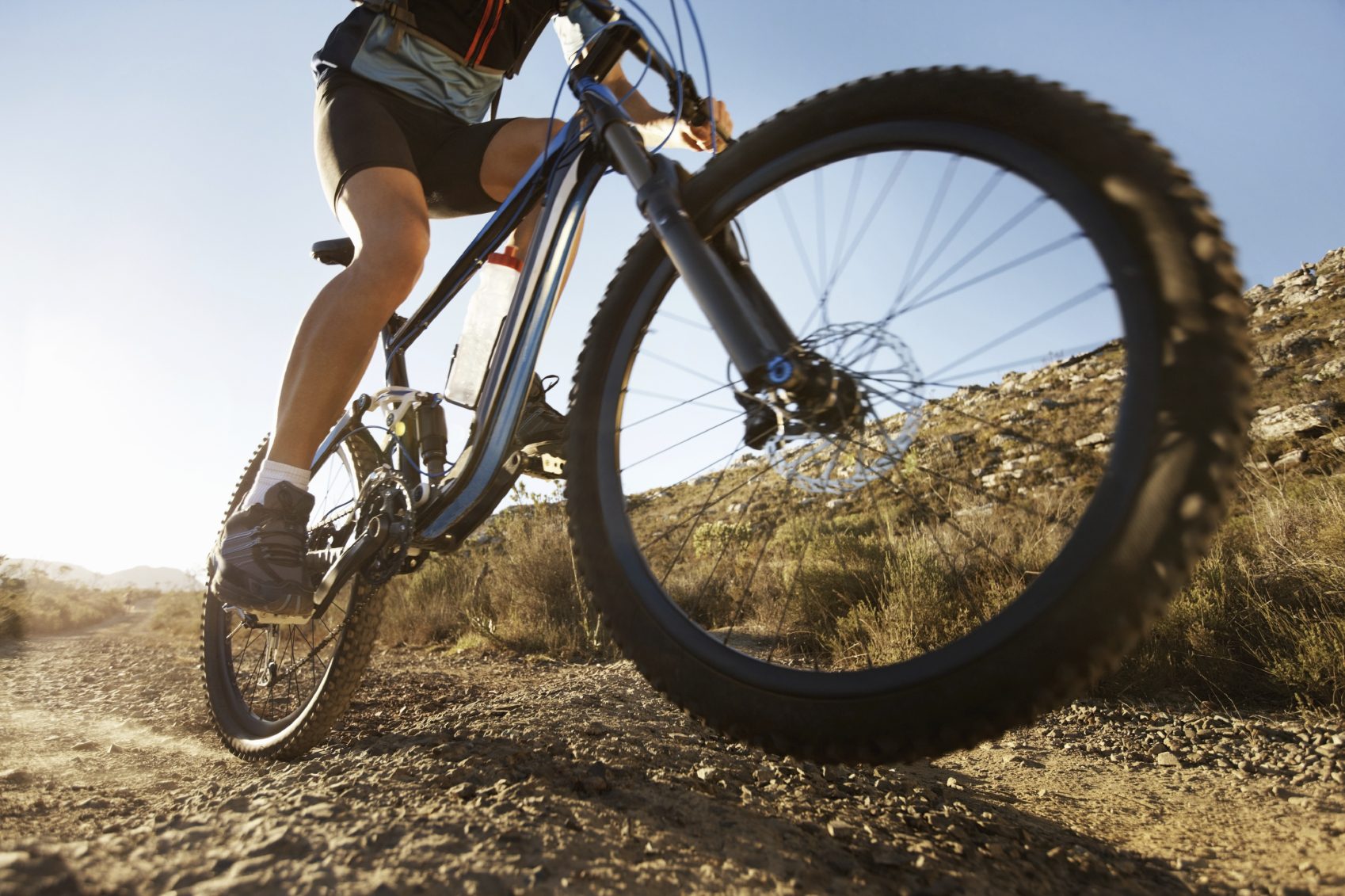 Mountainbiker fährt auf einem rauen, sonnendurchfluteten Weg.